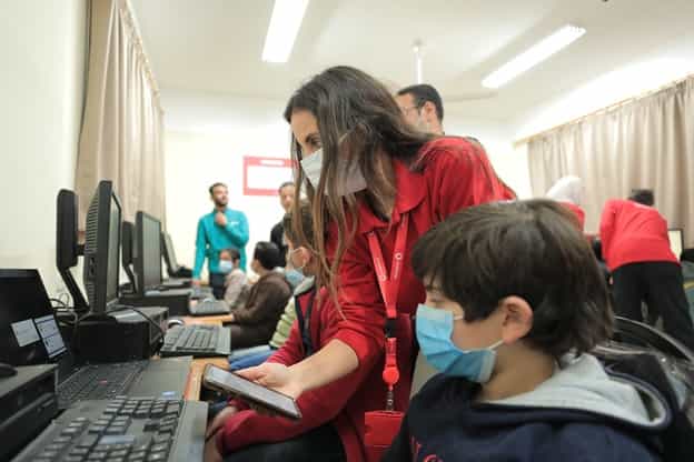 A vodafone female volunteer helping school boy