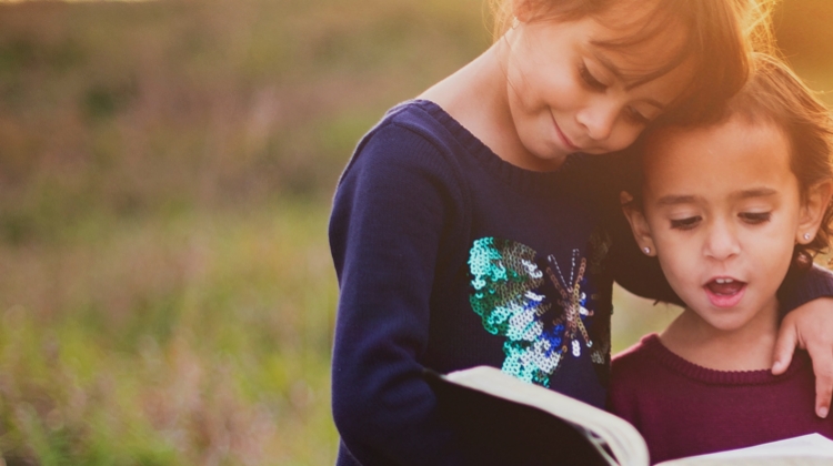 Two kids reading a book while smiling